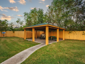 Guest covered BBQ area with grill, tables and seating, path and grassy areas