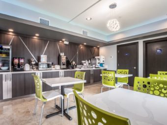 Tables and chairs, breakfast counter display with chilled cabinet, cereal dispensers, microwave, waffle machine, tiled flooring