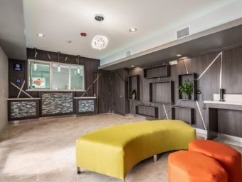 Guest check in desk behind glass partition, lobby seating, tiled flooring