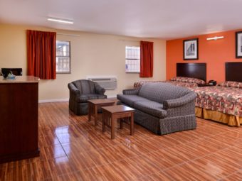 Two queen beds, night stand with telephone, sofa, easy chair, occasional tables, wooden unit, wall mounted flat screen tv, laminate flooring