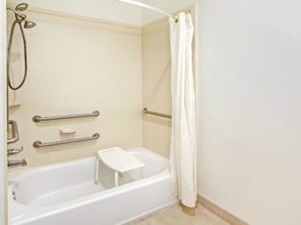 Shower tub, shower curtain, seat, grab handles, tiled flooring