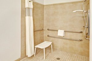 Walk in shower, shower curtain, seat, grab handles, tiled flooring