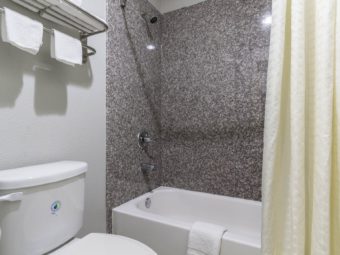 Shower tub with shower curtain, toilet, towel rail and shelf with towels