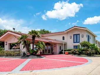 Two story building, hotel entrance with canopied drive through, landscaping with small trees and bushes