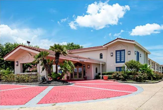 STXTC Exterior 2 Two story building, hotel entrance with canopied drive through, landscaping with small trees and bushes