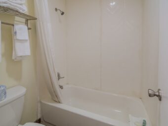 Shower tub with shower curtain, hanging rail with towels, toilet