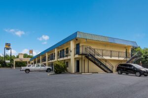 Brand signage, two story building with exterior walkways, stairs and guest room entrances, parking spaces