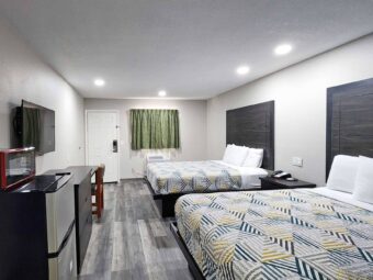 Two queen beds, fridge with microwave, wooden drawer unit, wall mounted TV, desk with chair, laminate flooring
