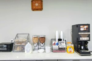 Toaster oven, breakfast pastries, bread, cereal, milk, juice, coffee machine