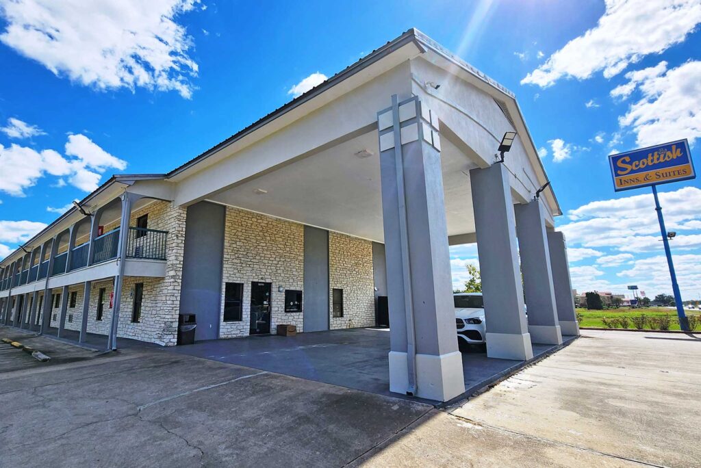 Hotel entrance with drive through canopy, two story building with covered walkways and exterior guest room entrances, brand signage