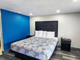 king bed, night stands with telephone, doorway leading to bathroom, laminate flooring