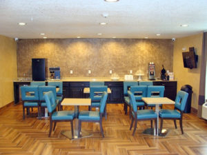 Tables and chairs, breakfast display counter with waffle machinem chilled cabinet, coffee machine, tiled flooring