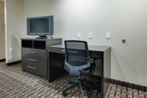 Desk with office chair, wooden drawer unit with tv, carpet flooring