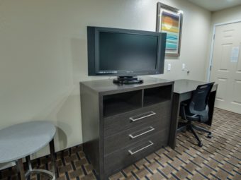 occasional table, wooden drawer unit with tv, desk with offfice chair, art image, carpet flooring