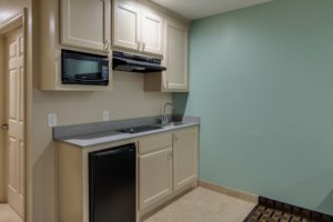 base and wall cabinets with microwave, cooker hood and fridge, counter top with hob and sink