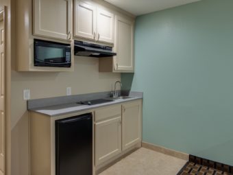 base and wall cabinets with microwave, cooker hood and fridge, counter top with hob and sink