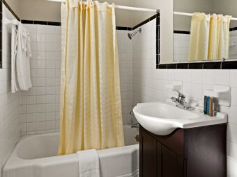 Shower tub with shower curtain, bath mat and towel rail with towels, vanity unit, mirror