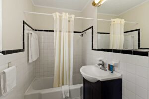 Shower tub with shower curtain, bath mat and towel rail with towels, vanity unit, mirror