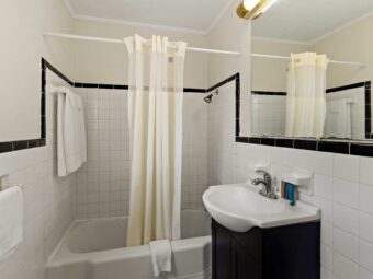 Shower tub with shower curtain, bath mat and towel rail with towels, vanity unit, mirror