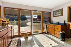 entrance to hotel lobby, small table, wooden unit with lamps, counter with snacks for purchase, tiled flooring