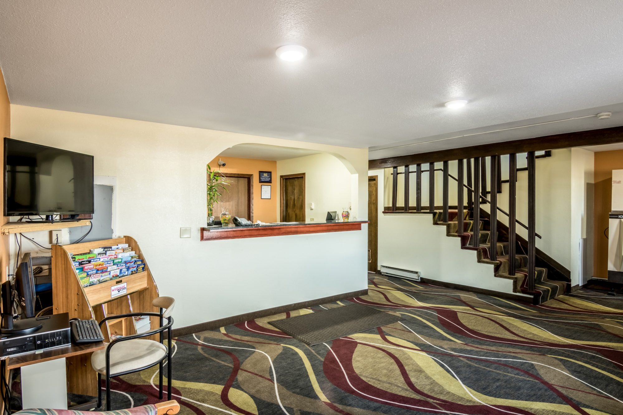 Guest check in desk, guest information leaflet stand, flat screen TV, stairs to next floor, carpet flooring